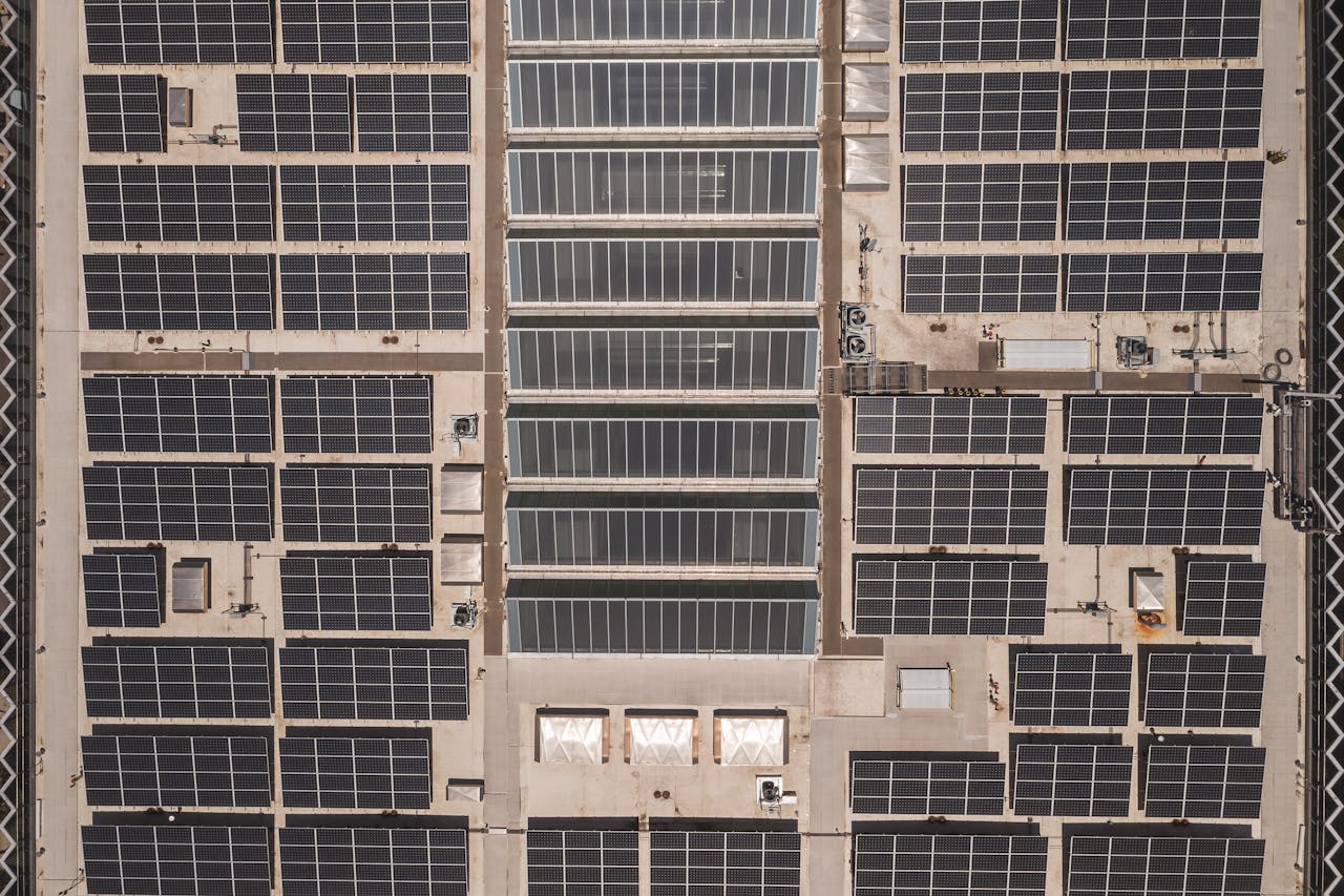 A high-angle drone shot capturing a grid of solar panels on a large industrial rooftop, showcasing renewable energy.